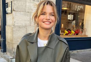 Paris woman wearing white t-shirt, jeans, and olive green jacket.