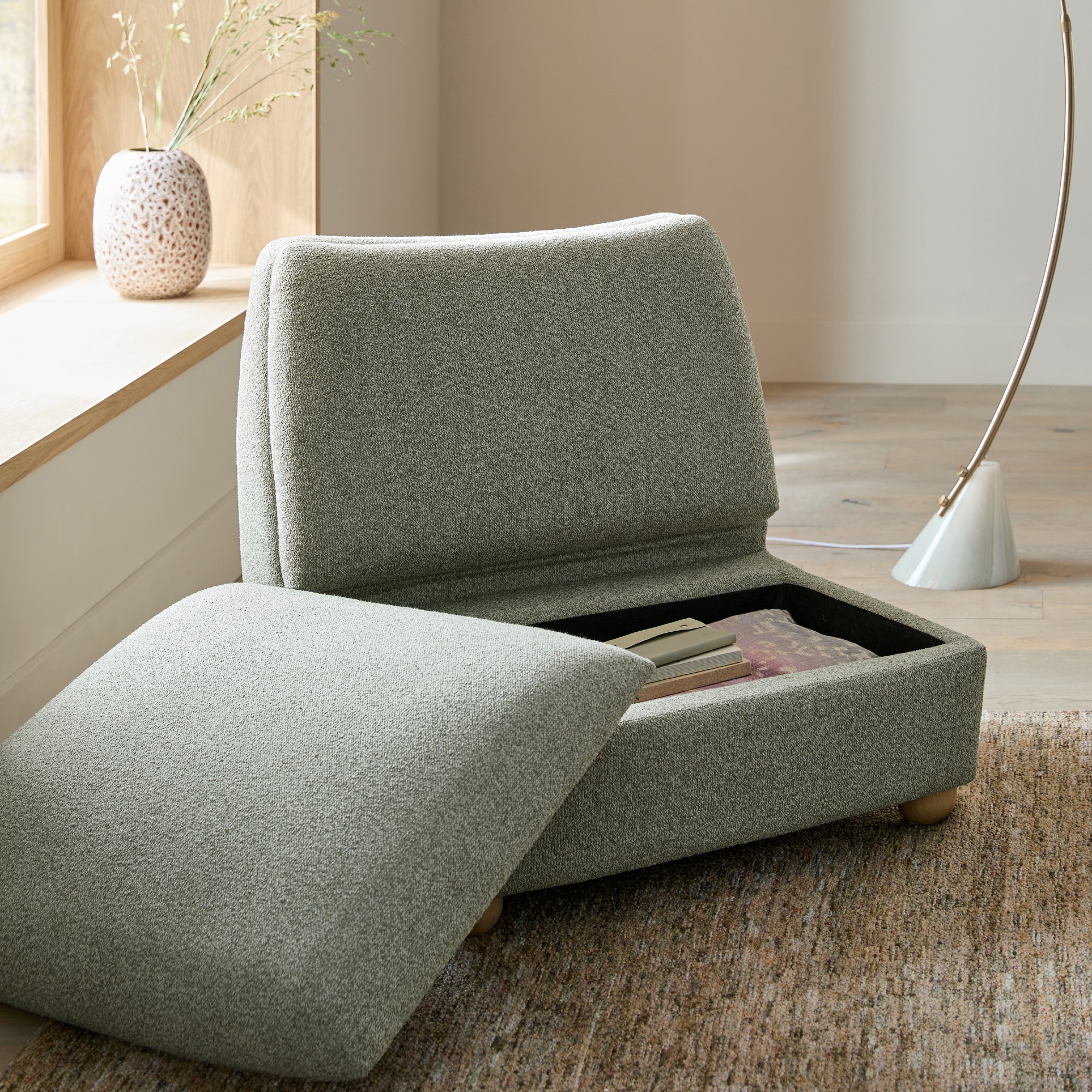 Next Clemmie storage accent chair in green open in a living room with a curved floor lamp behind it