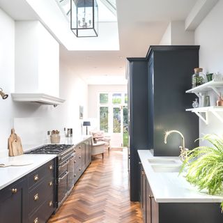 galley kitchen with herringbone wooden flooring and dark cabinetry