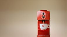 Illy ESE coffee maker in red on a beige background