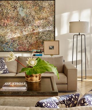 Living room with neutral sofa and coffee table, large artwork on wall and floor lamp