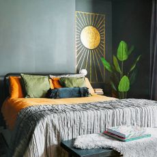 a black bedroom with metal framed bed and a gold sunshine decal on the wall