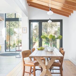 Dining area with table and chairs in extended home, with large swathes of glazing in the background