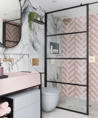 Pink herringbone wall tiles and a gray marble wall in a shower