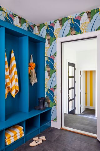 Colourful hallway, with bright blue bespoke cabinetry, patterned wallpaper and yellow stripy notes