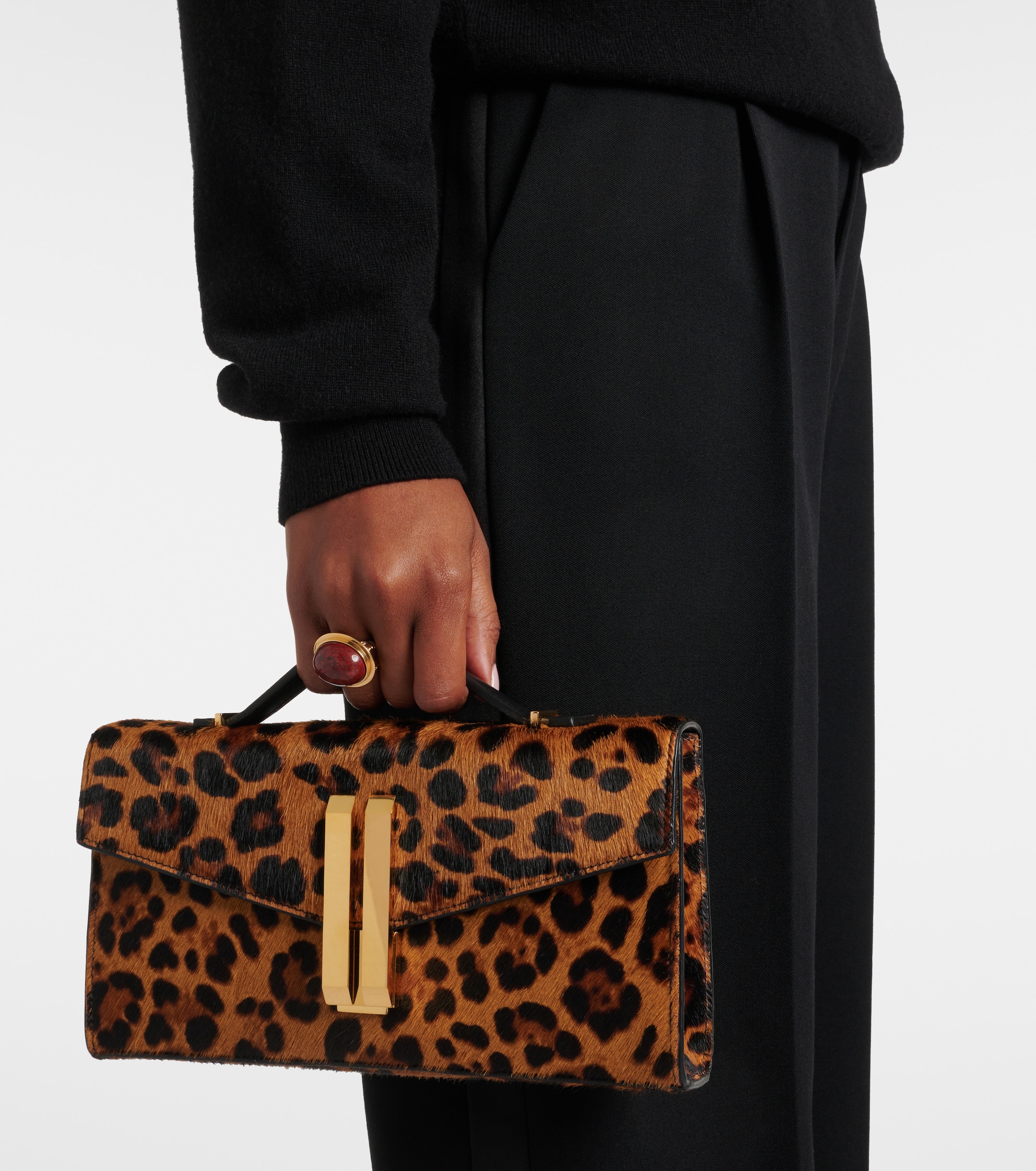 a model carrying a demellier leopard-print clutch