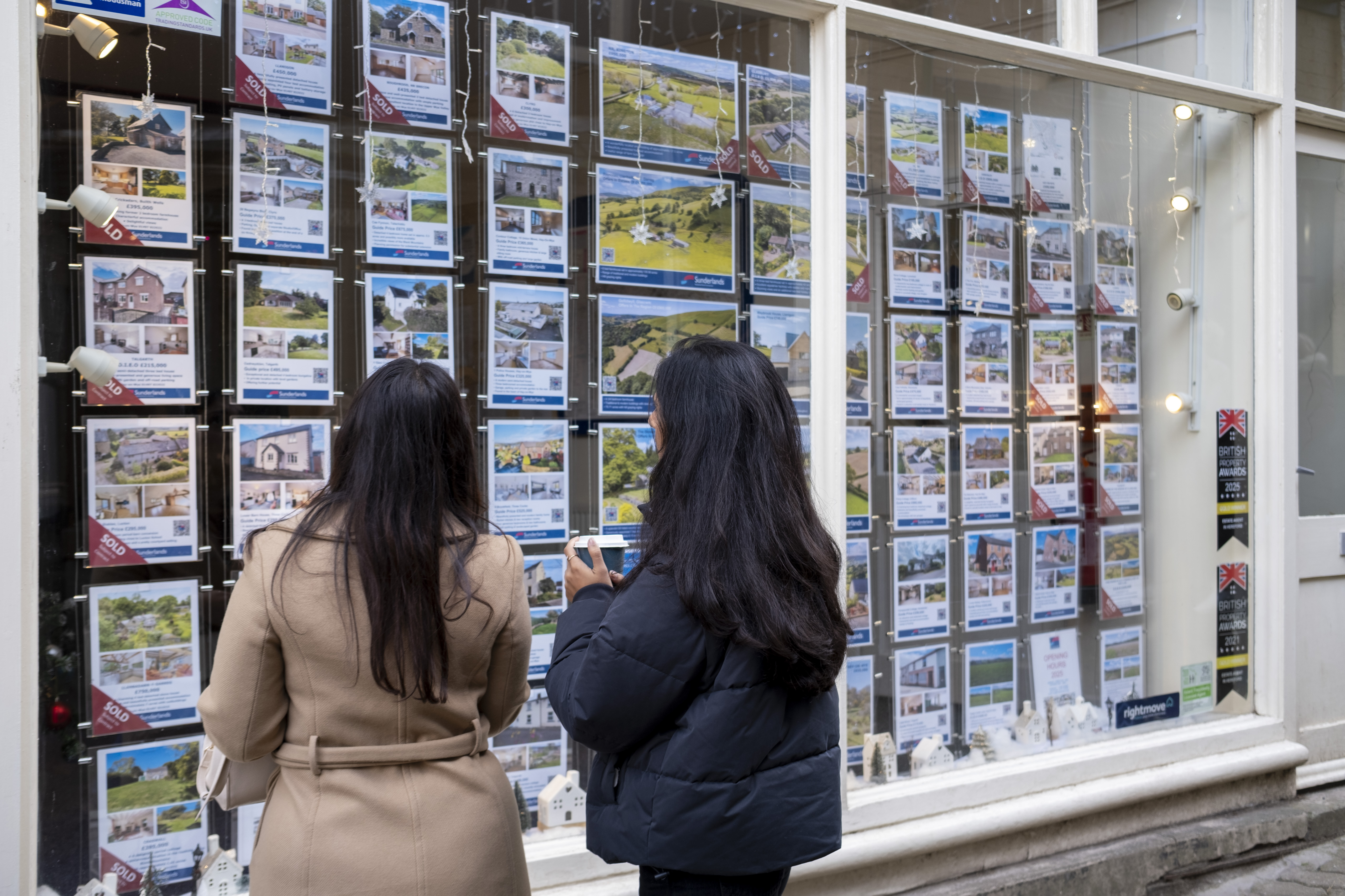 People looking through an estate agent's window