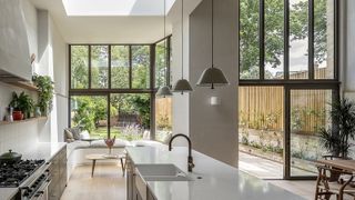 A wide angle shot of a downstairs kitchen extension with double-height ceilings and architectural glazing