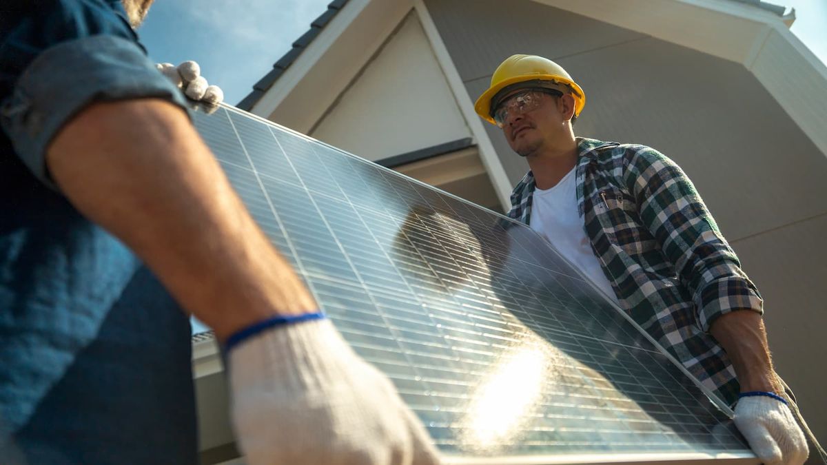 Solar panel installers carrying a solar panel