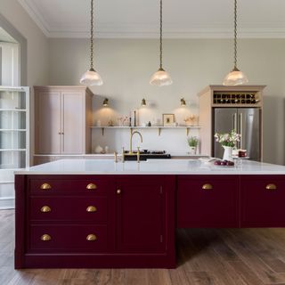Kitchen with oversized burgundy island and three pendant lights