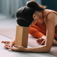 A woman doing one of the best 10-minute yoga workouts, resting her forehead on a yoga block
