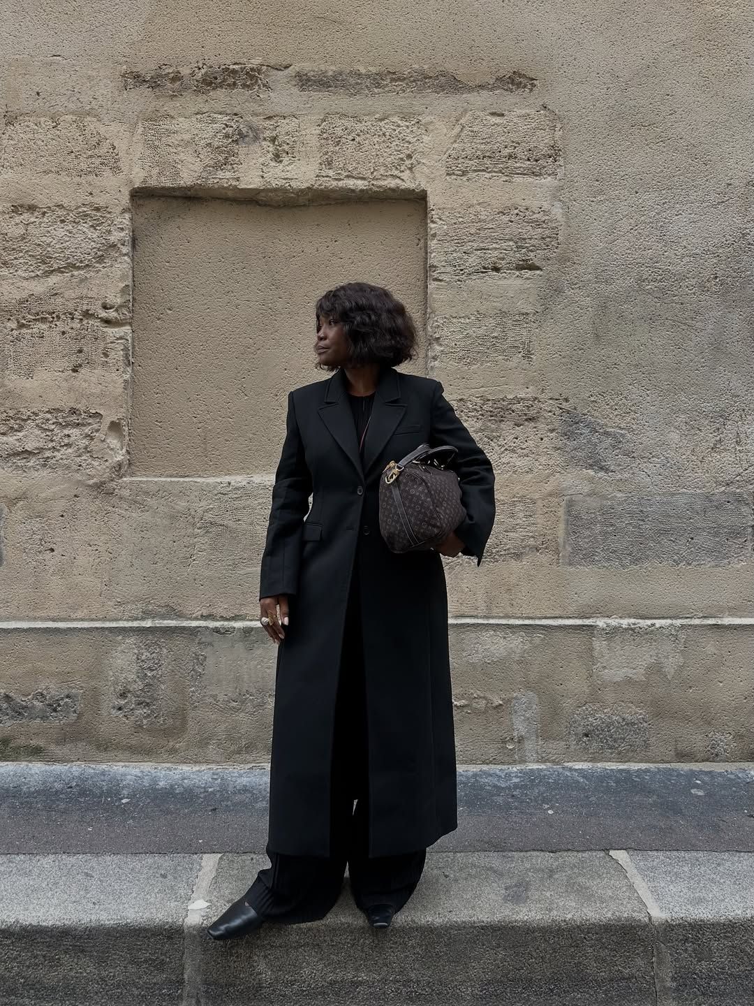 @frannfyne wearing a black coat and trousers