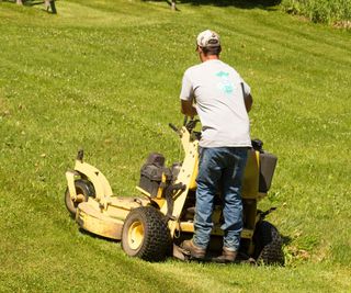 A man using a standing ride-on mower