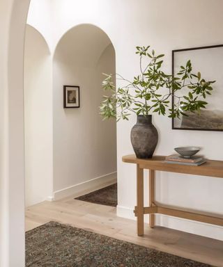 Wooden table, arched hallway in a white minimalist home