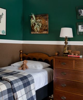 child's room with dark green upper walls, brown lower wall, wooden bed with plaid duvet cover