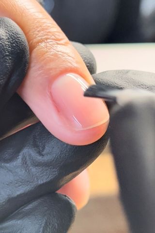 a clear base coat being applied to a nail
