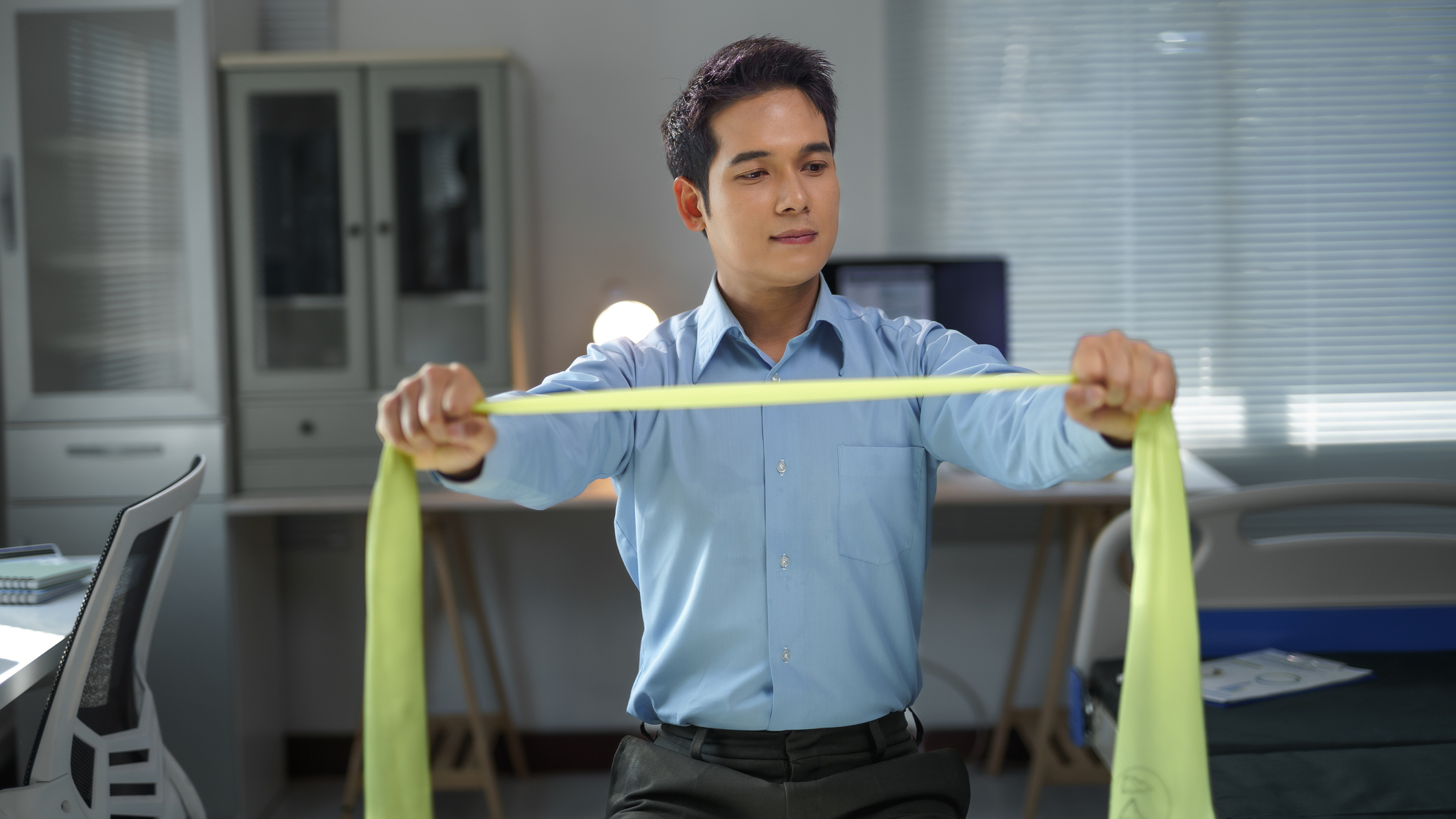 Man in business attire holds a resistance band in front of him 