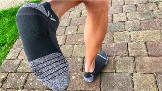 Man running on path wearing Swiftwick Flite XT Zero Tab trail running socks 