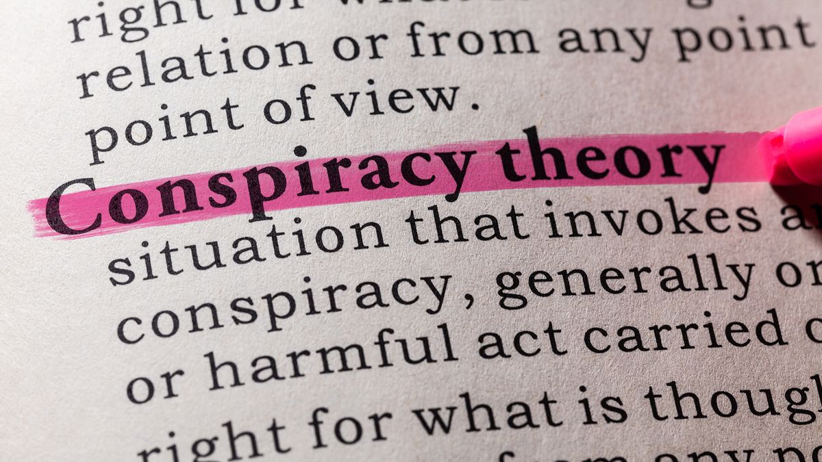 Close up of the term &#039;conspiracy theory&#039; highlighted in pink in a dictionary