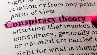 Close up of the term 'conspiracy theory' highlighted in pink in a dictionary