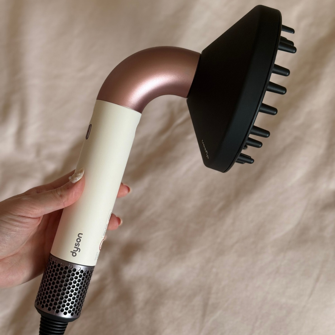 Handheld view of the Dyson Supersonic r Hair Dryer in Ceramic Pink with its diffuser