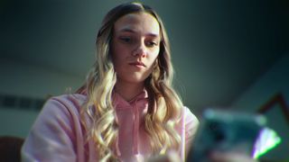 A girl looks down at the iPhone she is holding