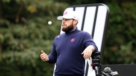 Tyrrell Hatton throws a golf ball up in the air while waiting on a tee box at LIV Golf Hong Kong