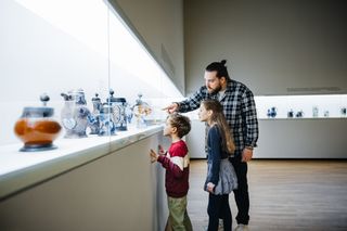 A father pointing to a museum exhibit with his children.