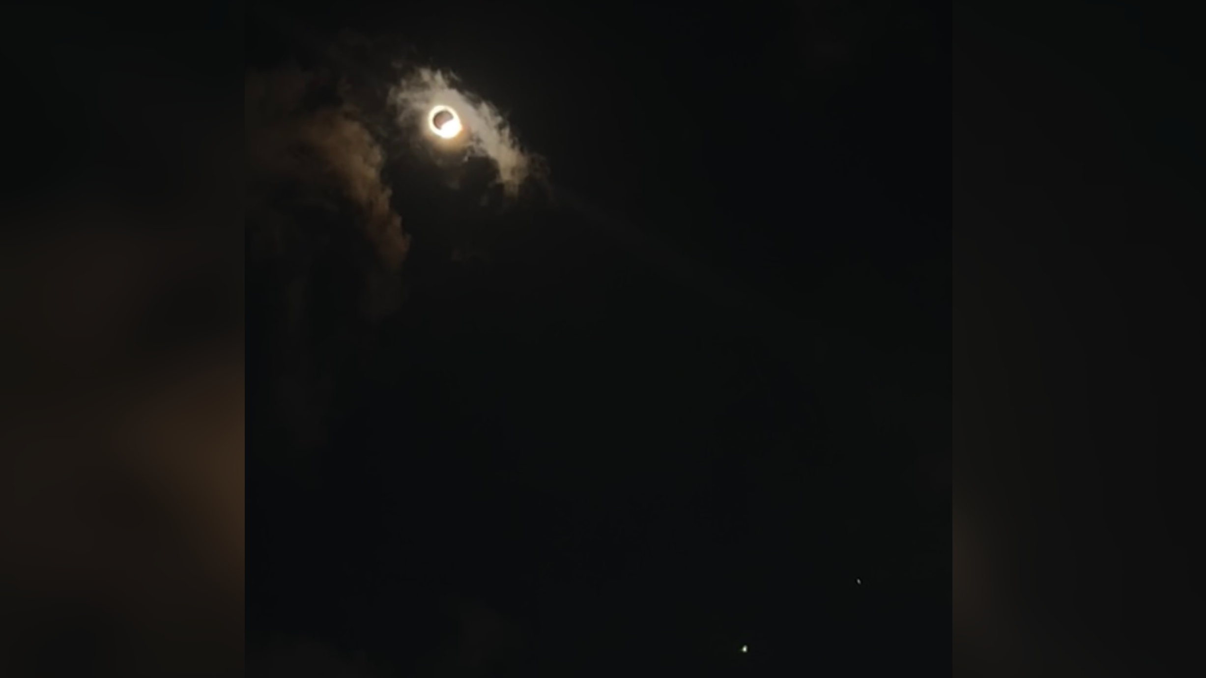 a bright point of light appears from behind the moon during the eclipse, making the scene look like a giant diamond ring in the sky.