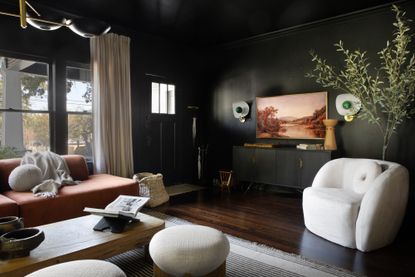 the best dark colors for small rooms; black living room with curved armchair by Urbanology Designs