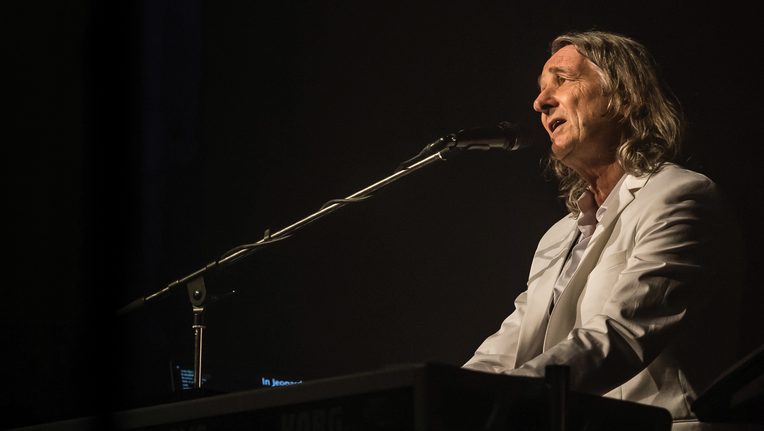 Roger Hodgson playing a piano on stage