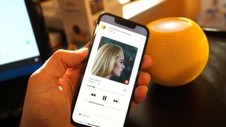 Apple Music on an iPhone, with a HomePod mini behind it
