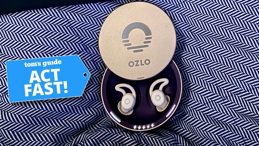 Ozlo Sleepbuds in silver circular case on blue and white patterned blanket