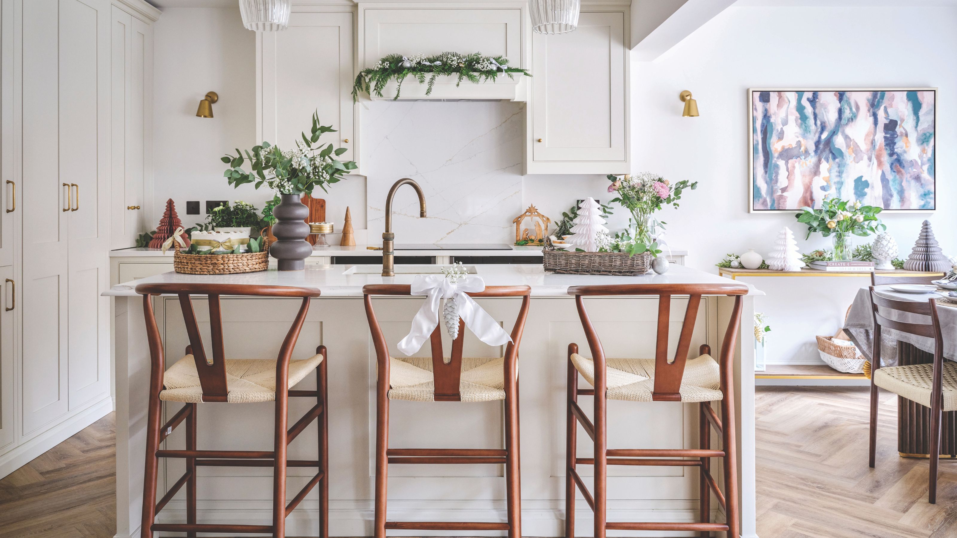 White kitchen with a large island and stools, decorated for christmas