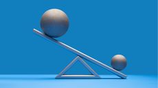 A bigger ball and a smaller ball are balanced on a seesaw-like scale.