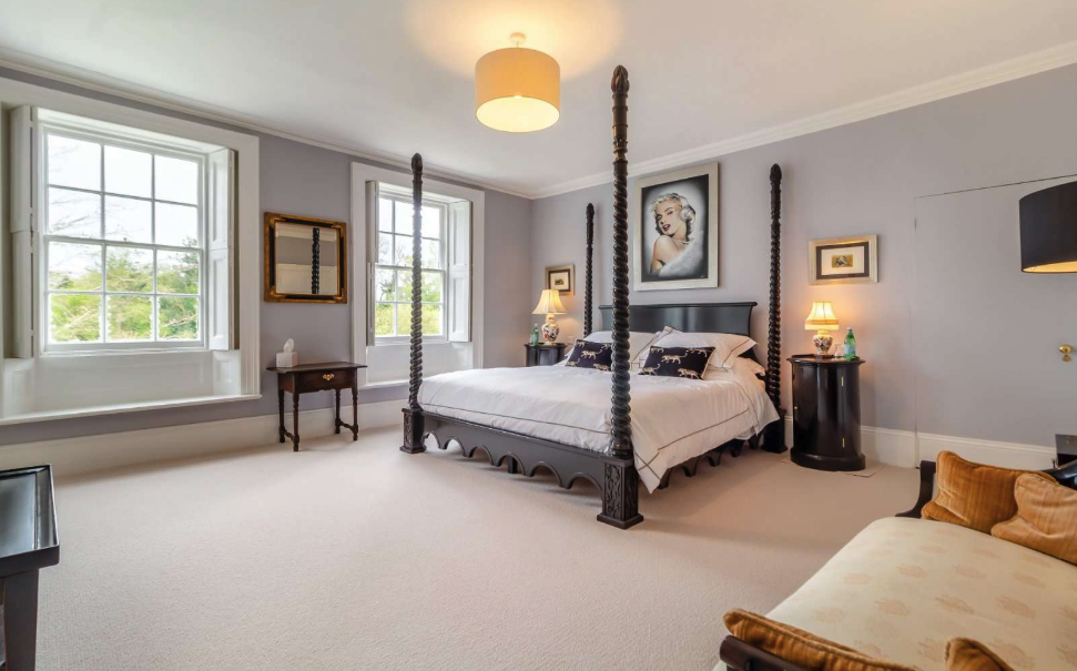 A bedroom in soft purple and blue, with a modern four-poster bed