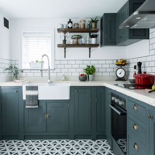 kitchen with white brick tiles wall rectangle wash basin with white marble countertop and kitchen crockery clock with fruits