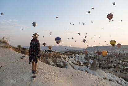 Young woman and hot air balloons in Cappadocia, Turkey, one of the cheapest countries to visit