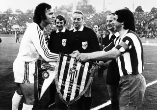 Bayern Munich captain and Atletico Madrid skipper Abelardo Rodriguez exchange club flags ahead of the 1974 European Cup final in Brussels.