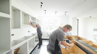 Builders in grey shirts fitting a new modern kitchen