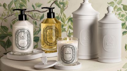 Diptyque Les Rituels de Soin collection on a white table with white wallpapered walls with vines