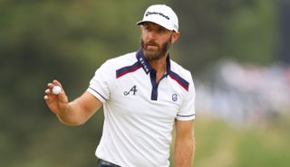 Dustin Johnson waves to the crowd after holing a putt