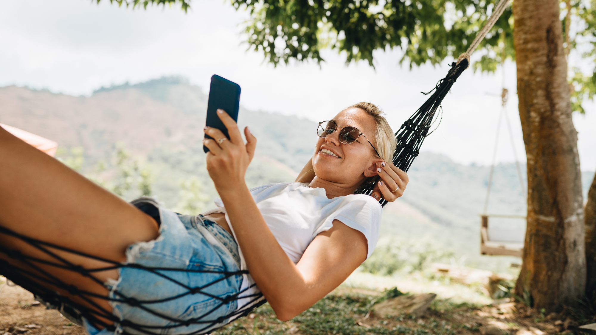 Person relaxing in a hammock using a phone