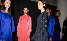 Models wear a range of high neck, embellished silk dresses in blue, navy and pink