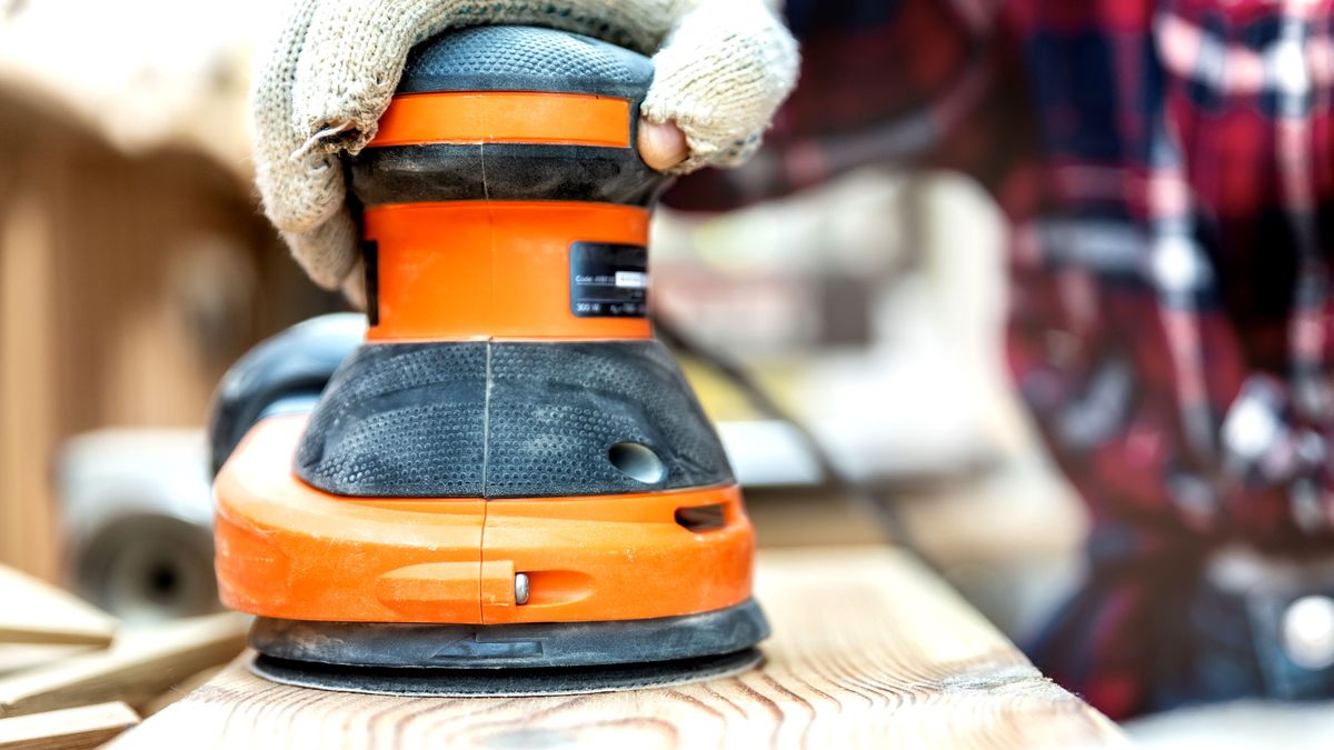 Front on view of orange orbital sander in action