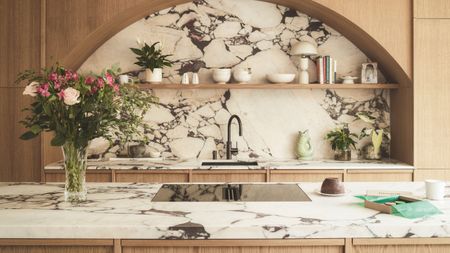 a kitchen with a marble island counter and backsplash with curved cabinetry