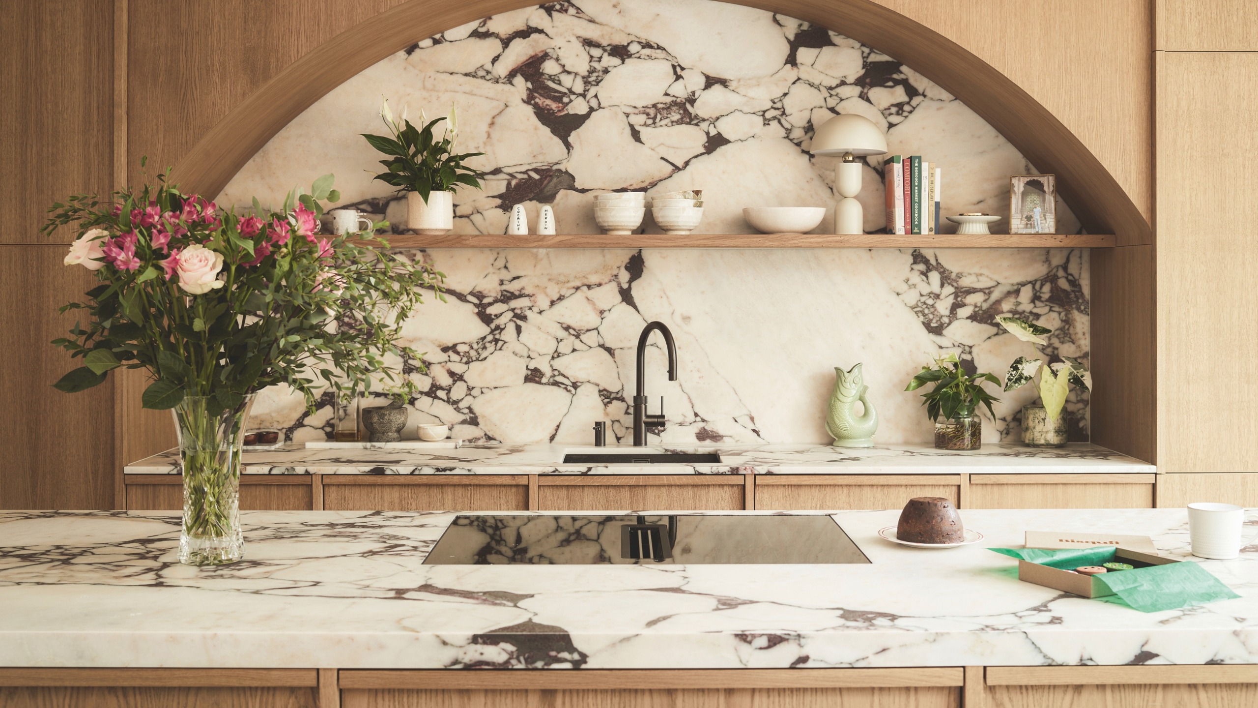 a kitchen with a marble island counter and backsplash with curved cabinetry