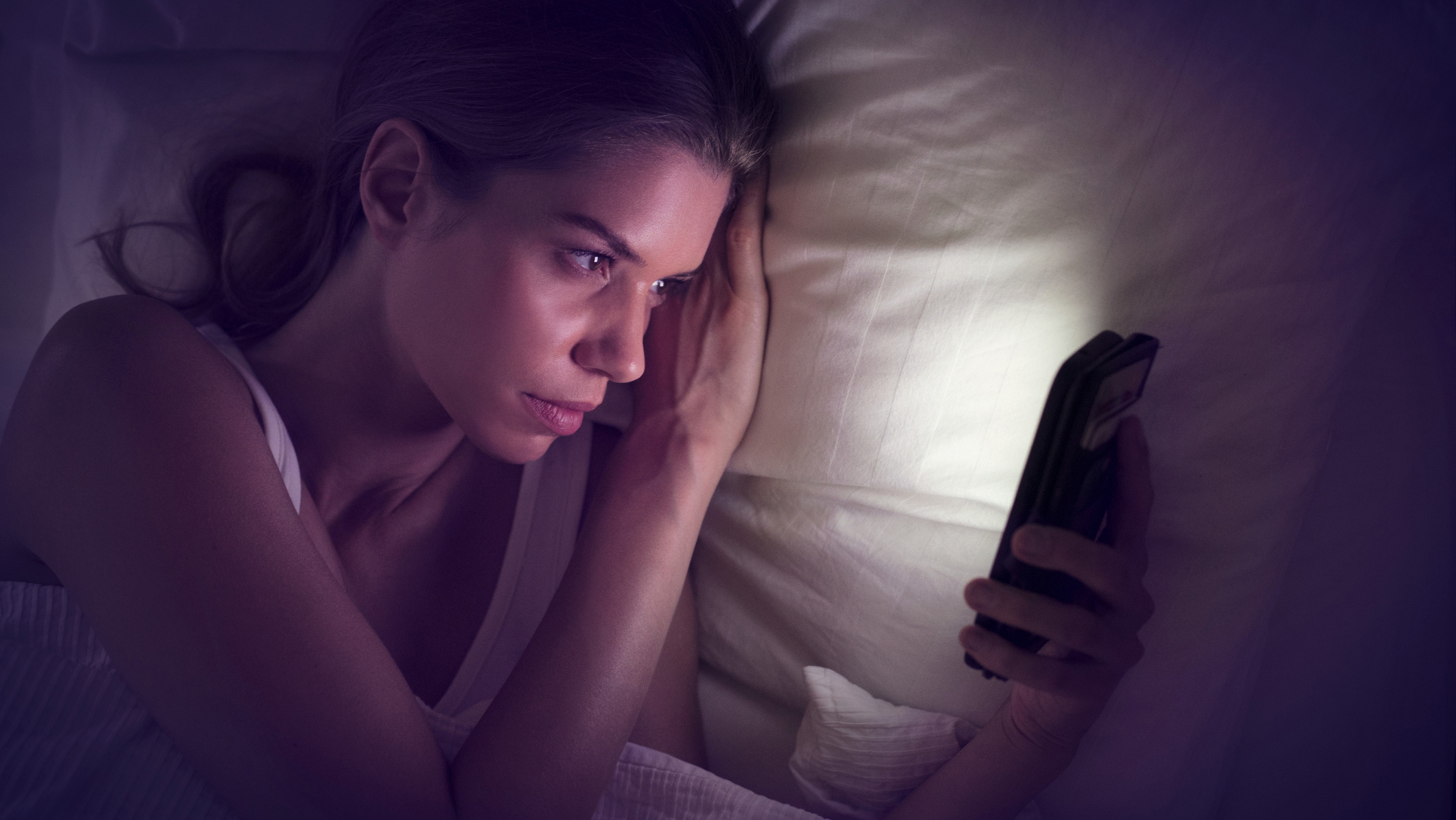 Женщина пользуется телефоном в постели ночью