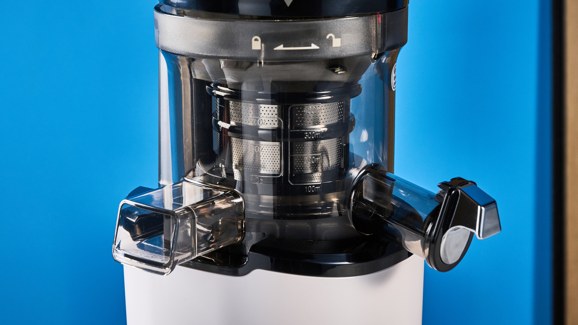 Kuvings Auto8 hands-free slow juicer photographed on a blue background.
