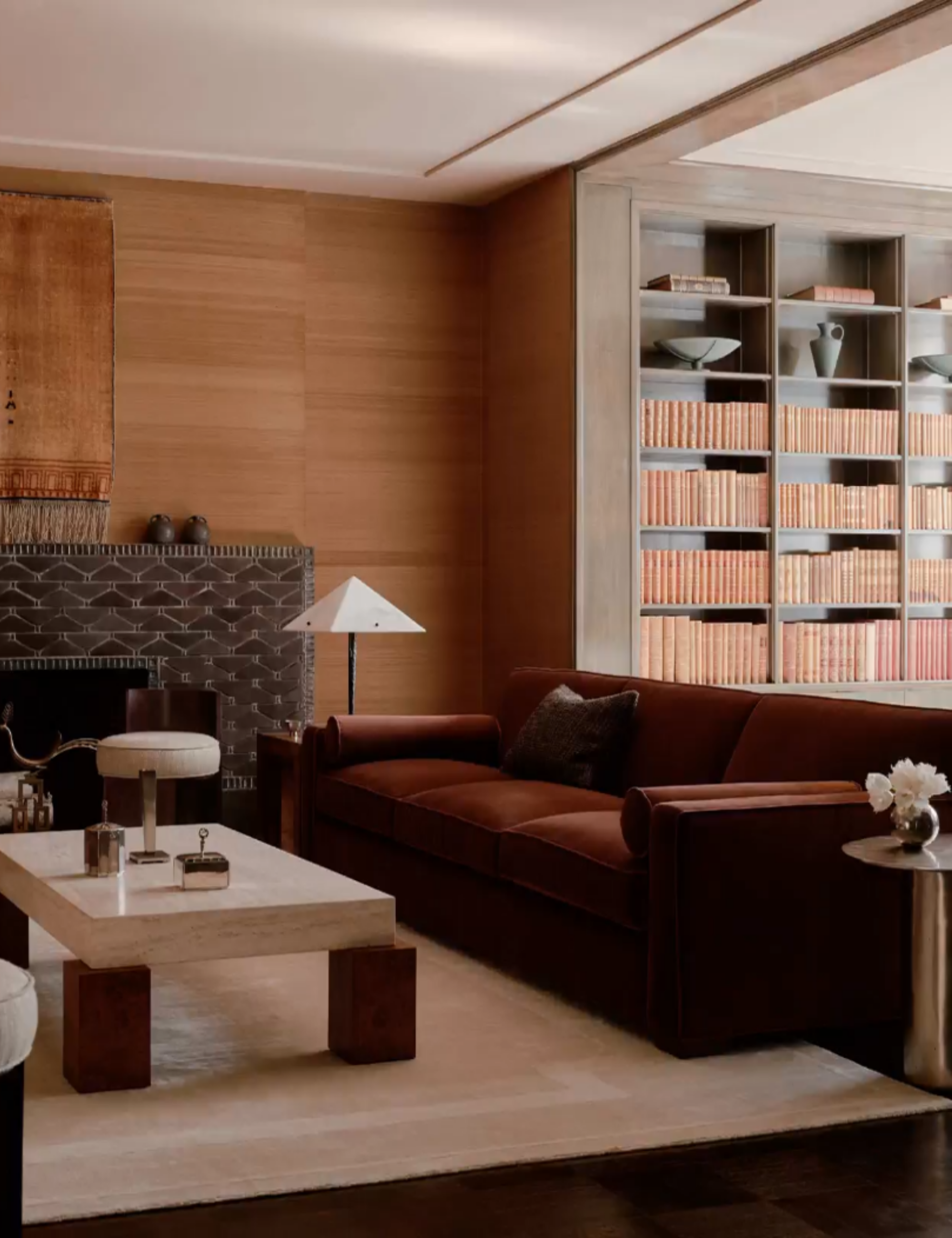 dark brown living room with large artwork, pendant light, a wooden coffee table and dark red velvet couch
